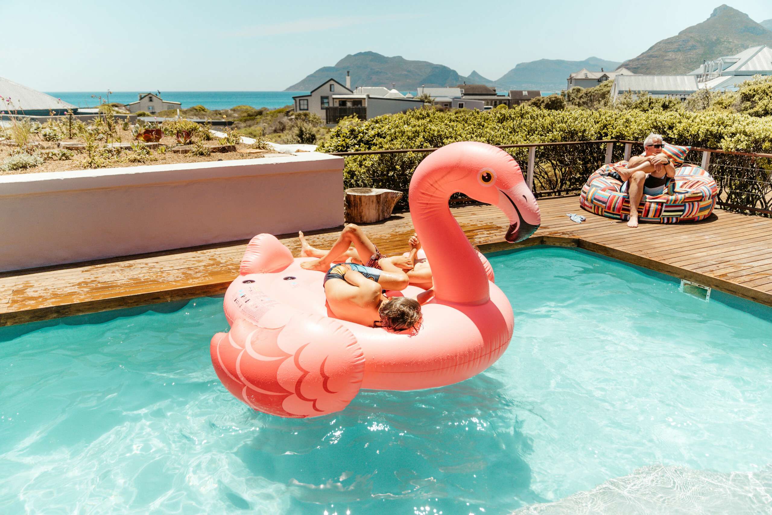 Children lounging on a giant pink flamingo float in Ballykom’s private pool with mountain and sea views