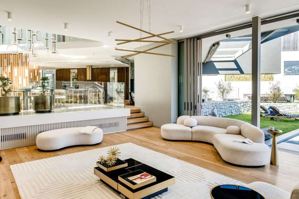 Elegant open-plan living room with curved designer sofas, contemporary lighting, and direct access to a garden and pool at Villa Serena.