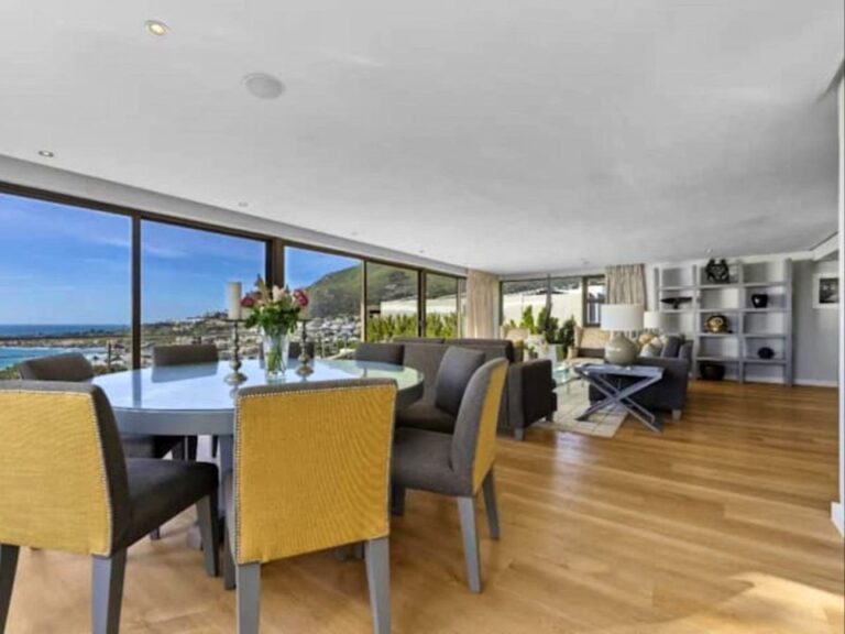 Bright open-plan dining and living area with floor-to-ceiling windows showcasing sweeping sea and mountain views at Azure Vista Villa