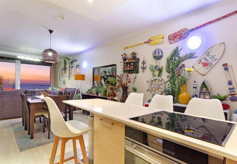 Open-plan kitchen and dining with colourful coastal décor and sunset views at Horizon Bay 1201