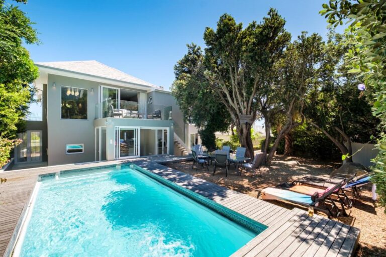 Inviting pool and garden area with sun loungers and shaded trees at Serein