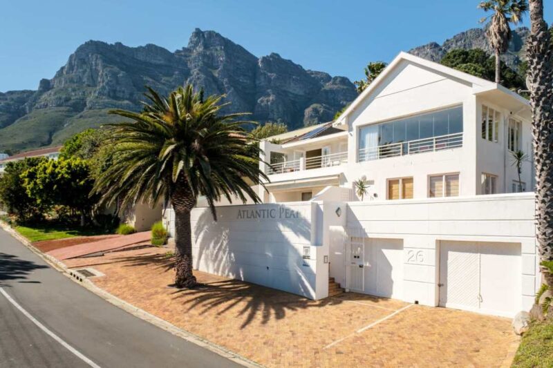 Modern white villa exterior with mountain backdrop and palm tree at Atlantic Gem