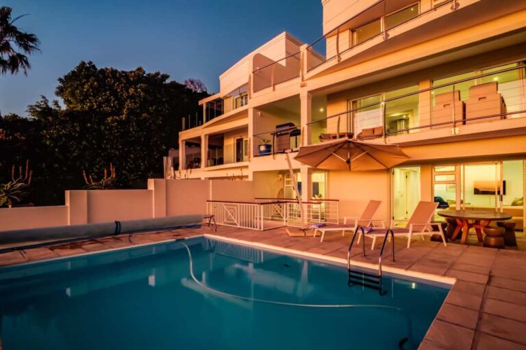 Sunlit pool terrace with loungers and sea-facing balconies at Alpha on the Bay