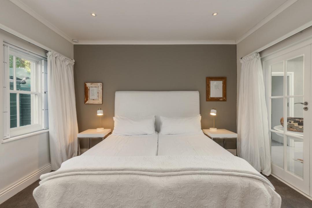 Cozy neutral bedroom with white bedding soft lighting and double windows Villa Galazzio