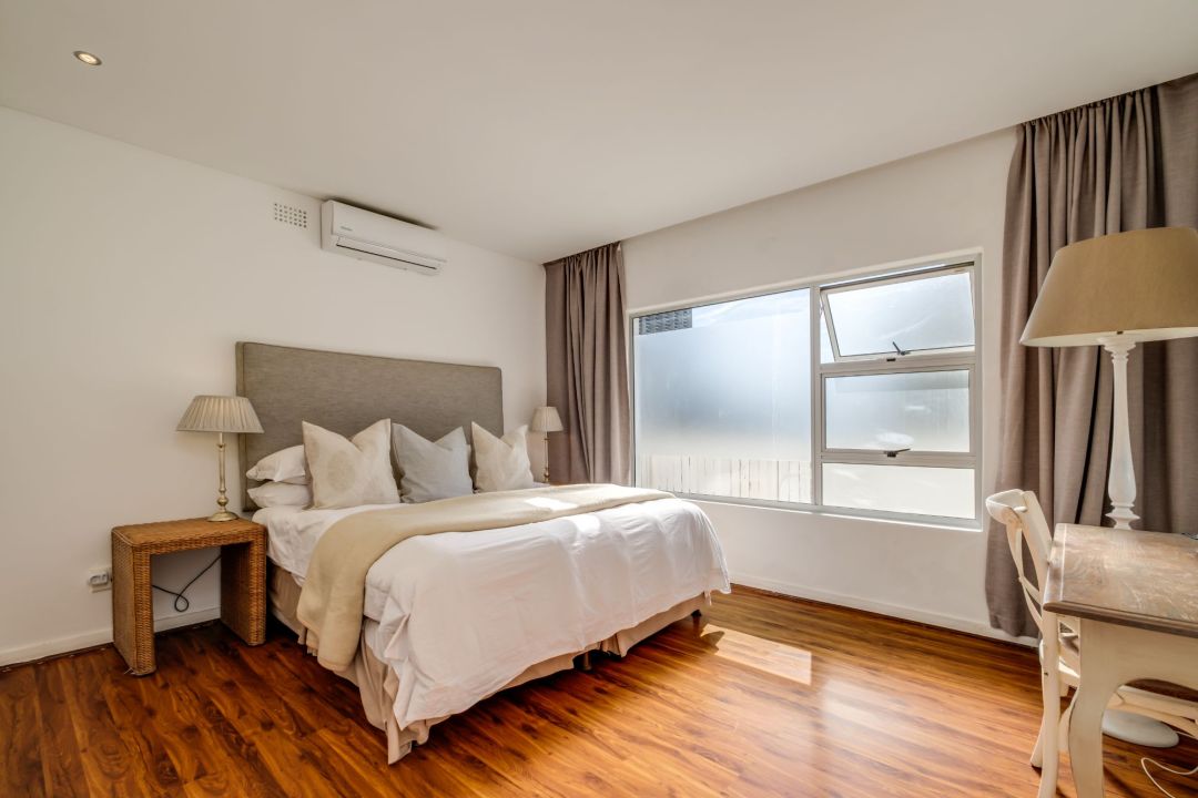 Sunlit bedroom with plush bedding and wooden flooring at Silvertree