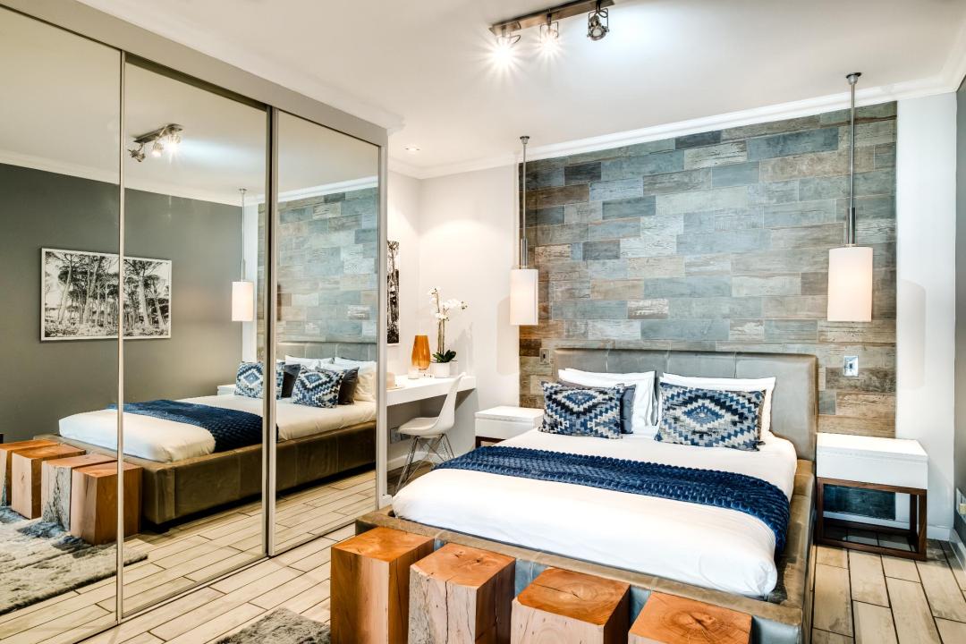 Designer bedroom with textured feature wall and mirrored wardrobes at Stonewood