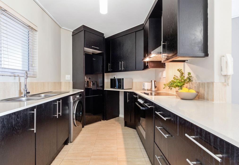 Sleek Galley-Style Kitchen with Dark Cabinetry at Lagoon Beach 29A