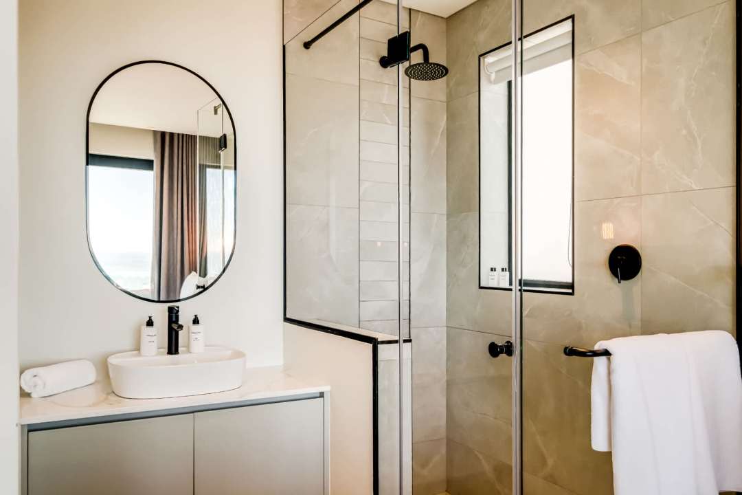 Modern glass-enclosed shower and sleek vanity at Marula One