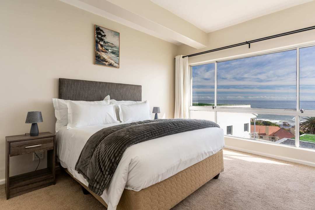 Serene sea-facing bedroom with large picture window at Caprice Bay