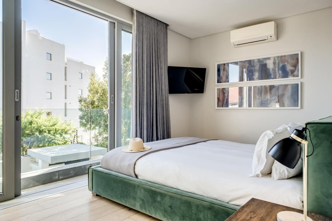 Sunny Modern Bedroom with Balcony Access and Green Velvet Bed at Nobelium